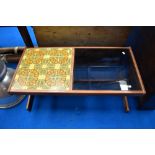 A vintage teak coffee table having tiled and smoked glass top