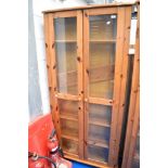 A modern pine glass fronted slim bookcase