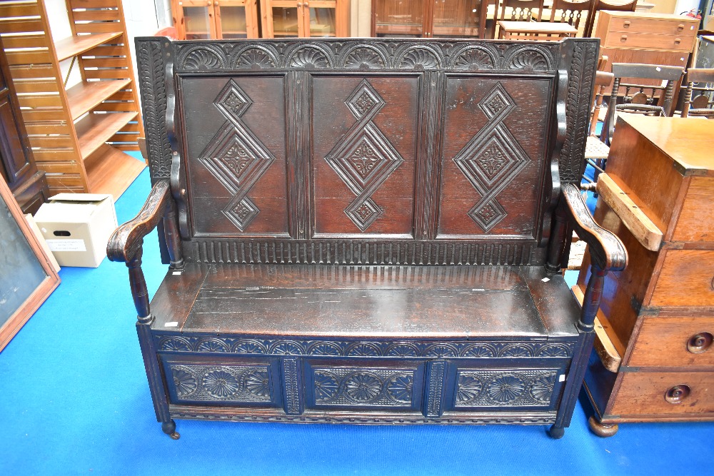 A 19th Century dark oak three panel monks bench/settle having carved decoration