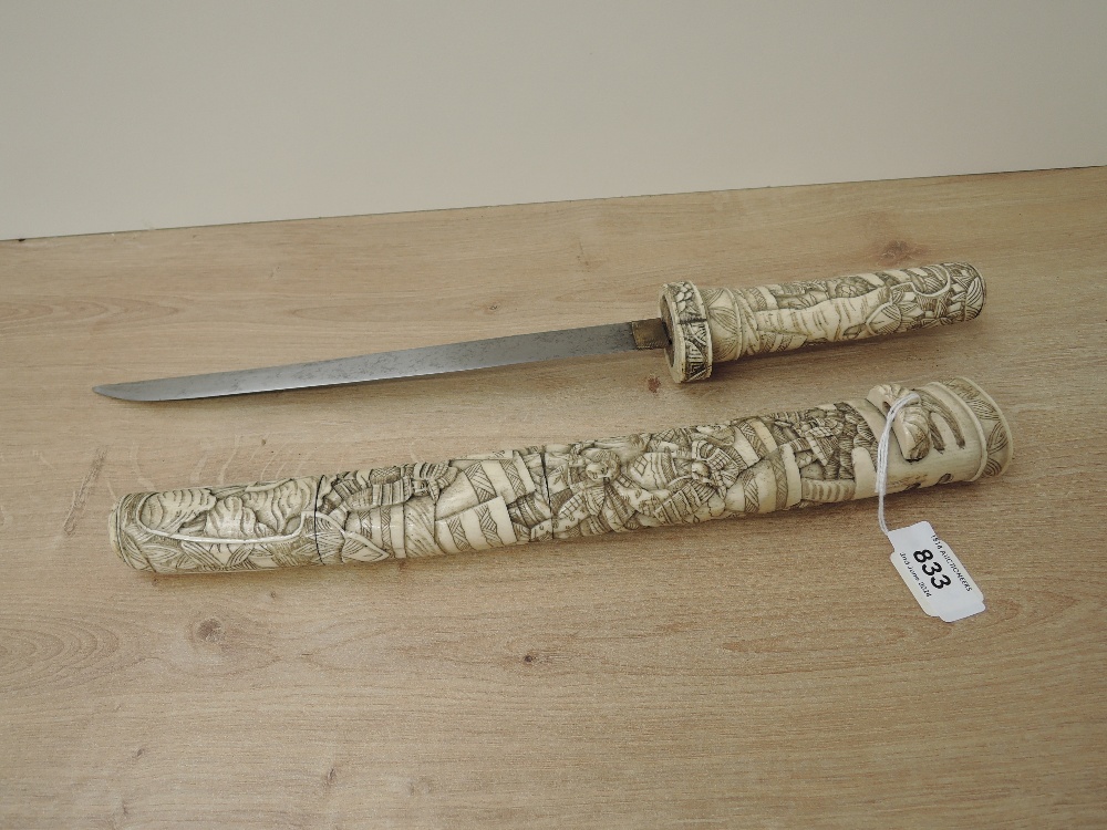 A Japanese Dagger with highly carved bone hilt and scabbard depicting Samurai Warriors, blade length