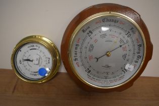 Two modern round barometers, one small porthole style and another with a wooden base.
