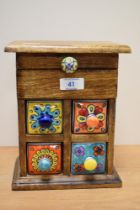 An unusual hardwood and ceramic miniature set of drawers, for jewellery and trinkets, with four