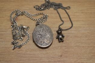 A large silver locket with foliage motif decoration with multiple frames on a silver curb link