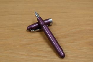 A Noodlers Ink plunger fill fountain pen in purple with a Noodlers Ink Co. nib.