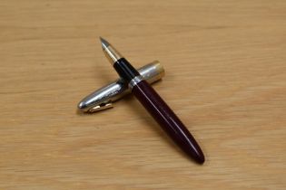 A Sheaffer Sentinal Tuck Away plunger fill fountain pen in burgundy with silver cap with gold trim
