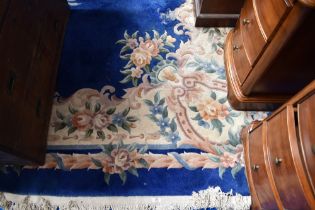 A vintage Chinese carpet square having blue ground with floral pattern and fringed edge, approx