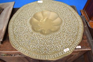 An Eastern brass table top, having scalloped centre, approx 61cm diameter.