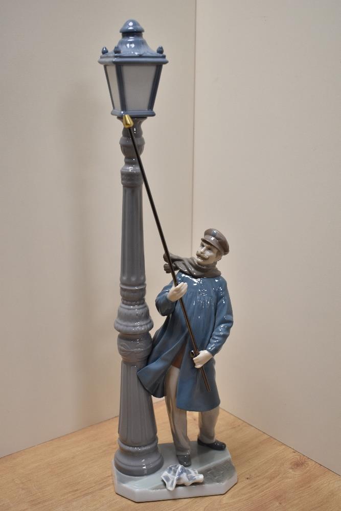 A Lladro porcelain figure 'Lamplighter' number 5205, modelled as a windswept gentleman lighting a