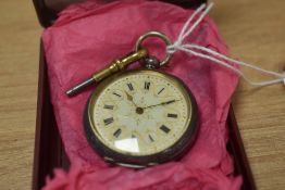 A small open face key wound pocket watch, the white dial having Roman numerals within gold circles
