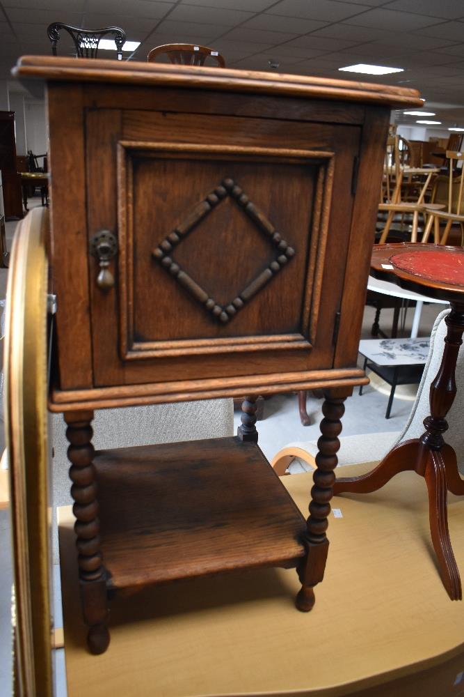 An early 20th century oak pot cupboard with moulded square top, moulded panel door and turned legs