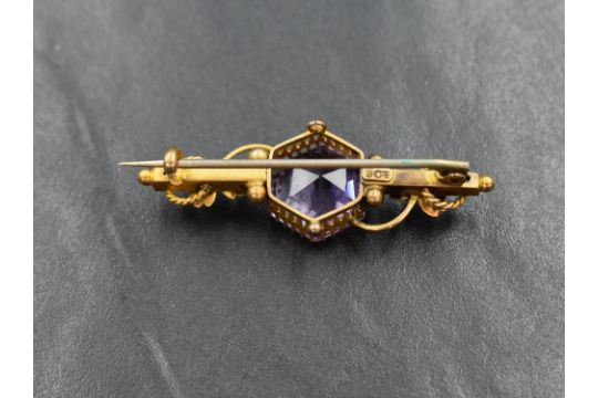 A yellow metal bar brooch stamped 9ct having central hexagonal amethyst in decorative floral mount - Image 2 of 3