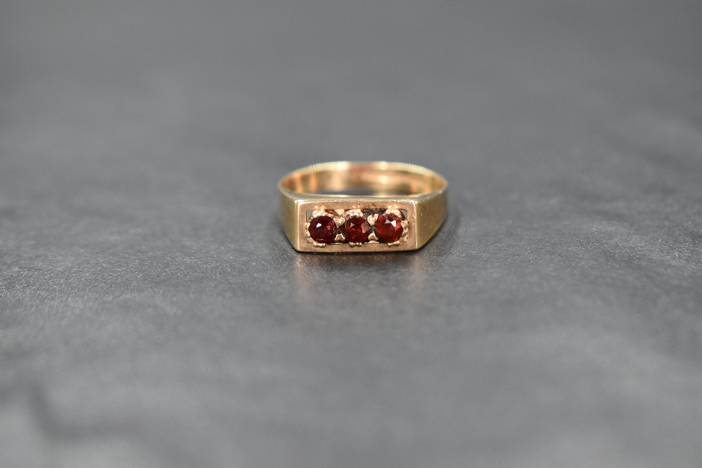 A 9ct gold garnet trilogy ring having a claw set mount in a box style setting, size N & approx 2.4g