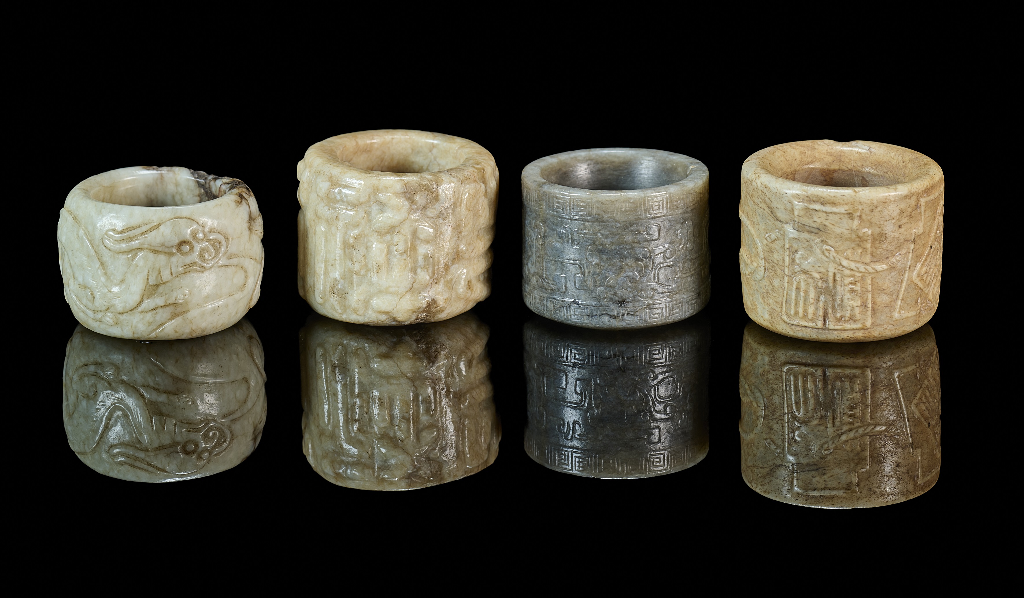 A GROUP OF FOUR CHINESE CARVED JADE ARCHERS RINGS, QING DYNASTY, 19TH CENTURY