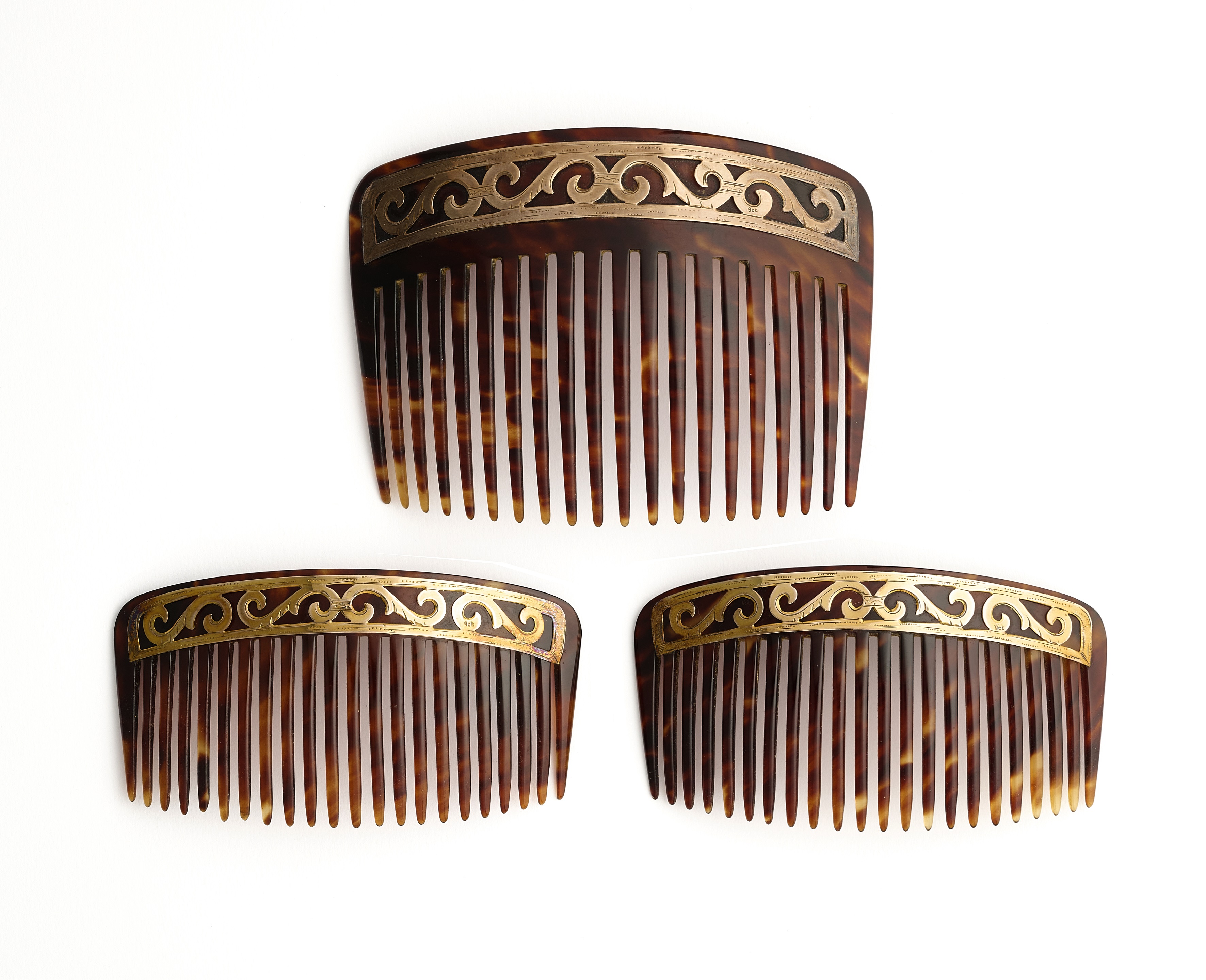˜ □ A SET OF THREE EDWARDIAN TORTOISESHELL AND GOLD HAIR COMBS, 1900s
