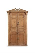 A 19TH CENTURY STRIPPED PINE CUPBOARD WITH ARCHITECTURAL PEDIMENT, above twin fielded panel