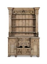 AN IRISH STRIPPED PINE KITCHEN DRESSER, the carved and pierced frieze above open shelves on a