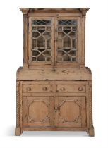 A PINE BUREAU BOOKCASE, the plain frieze top above twin glazed cupboard doors each with inset