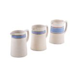 A SET OF THREE CARRIGALINE POTTERY JUGS in various sizes, with a large mug, plain cream with