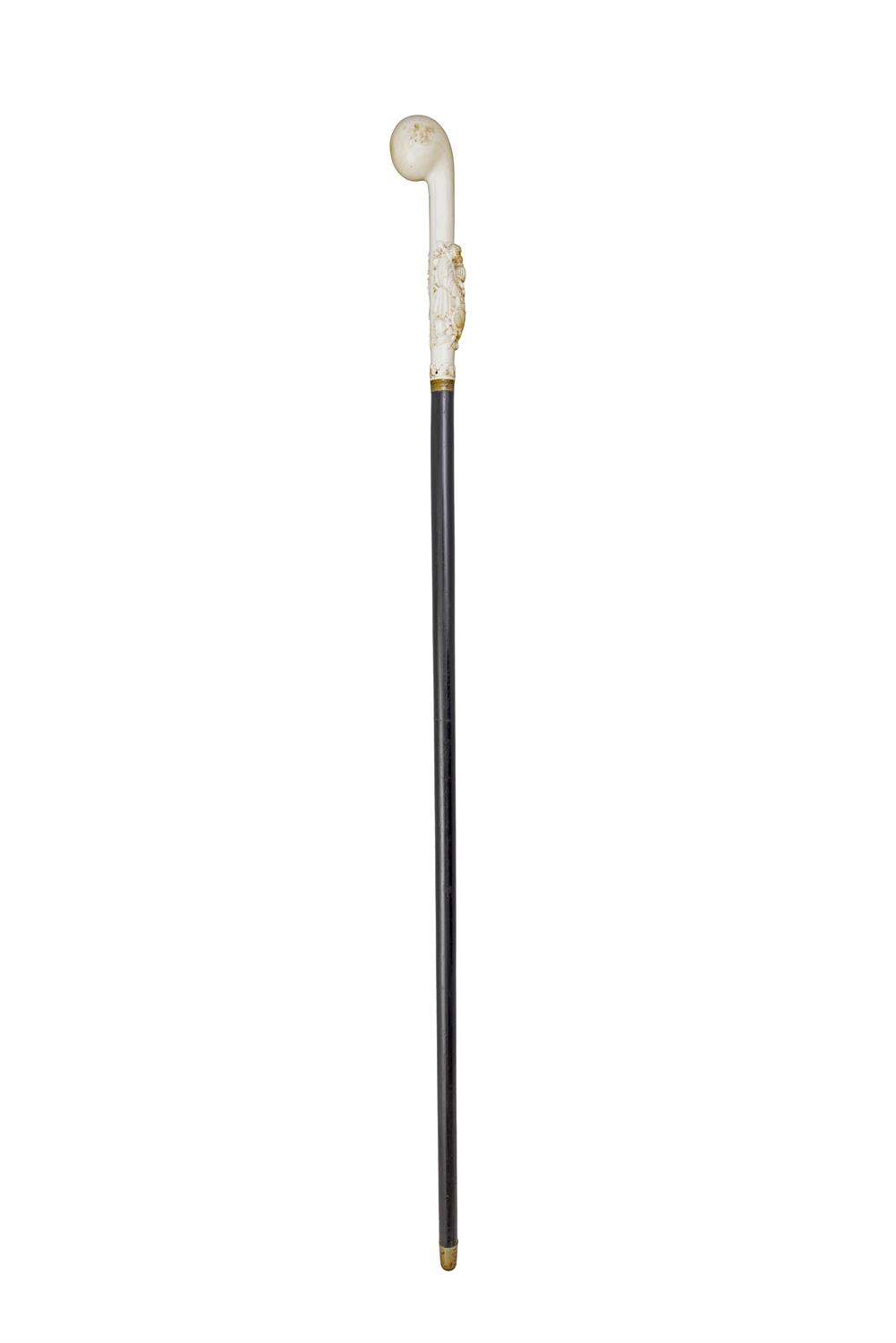 *A WALKING CANE, the ivory 'fist handle' top, with elaborately carved coat of arms,