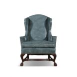 AN UPHOLSTERERED MAHOGANY FRAMED WINGBACK ARMCHAIR C.1920 covered In teal leather,