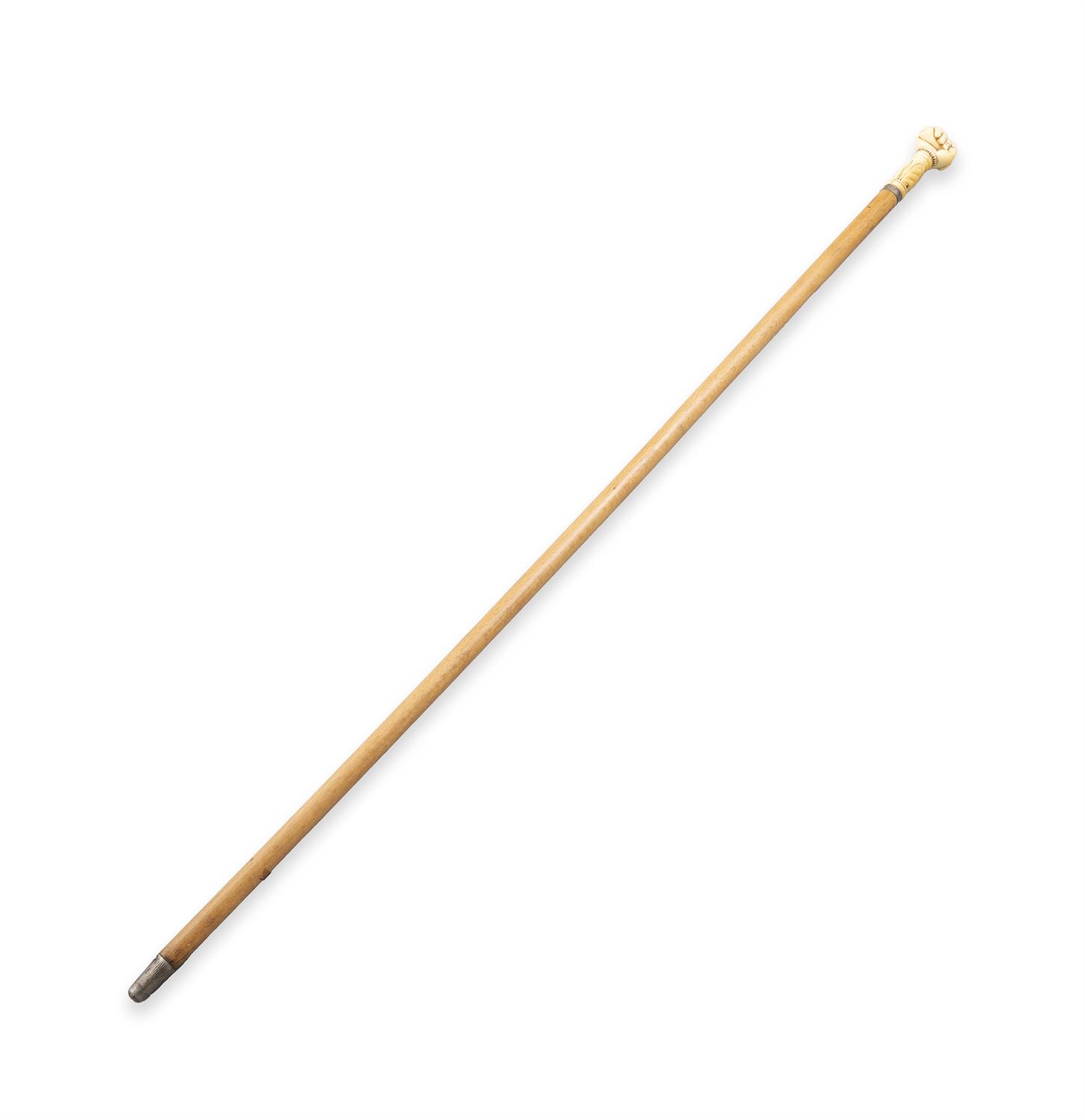 *A WOODEN WALKING CANE, with carved ivory handle in the shape of a fist enclosing a seal,