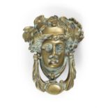 A GEORGIAN STYLE BRASS DOOR KNOCKER IN THE FORM OF A CLASSICAL FEMALE MASK, with leaf sing