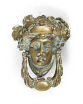 A GEORGIAN STYLE BRASS DOOR KNOCKER IN THE FORM OF A CLASSICAL FEMALE MASK, with leaf sing