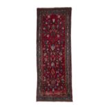 AN IRANIAN RED GROUND WOOL RUNNER, 275 x 105cm the central field decorated with floral pattern