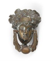 A GEORGIAN STYLE BRASS DOOR KNOCKER IN THE FORM OF A CLASSICAL FEMALE MASK, with leaf sing