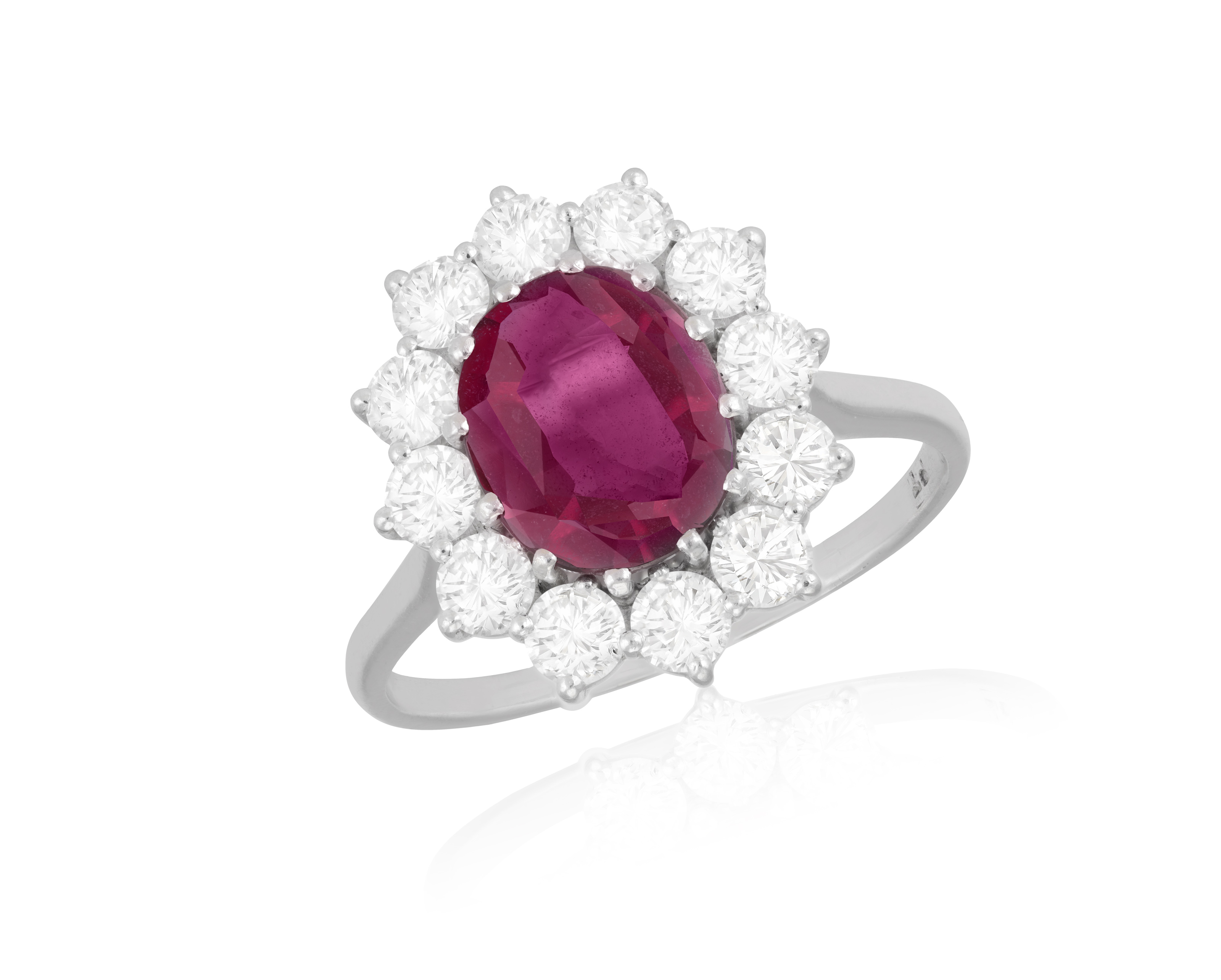 A RUBY AND DIAMOND CLUSTER RING The oval-shaped ruby within a brilliant-cut diamond surround,