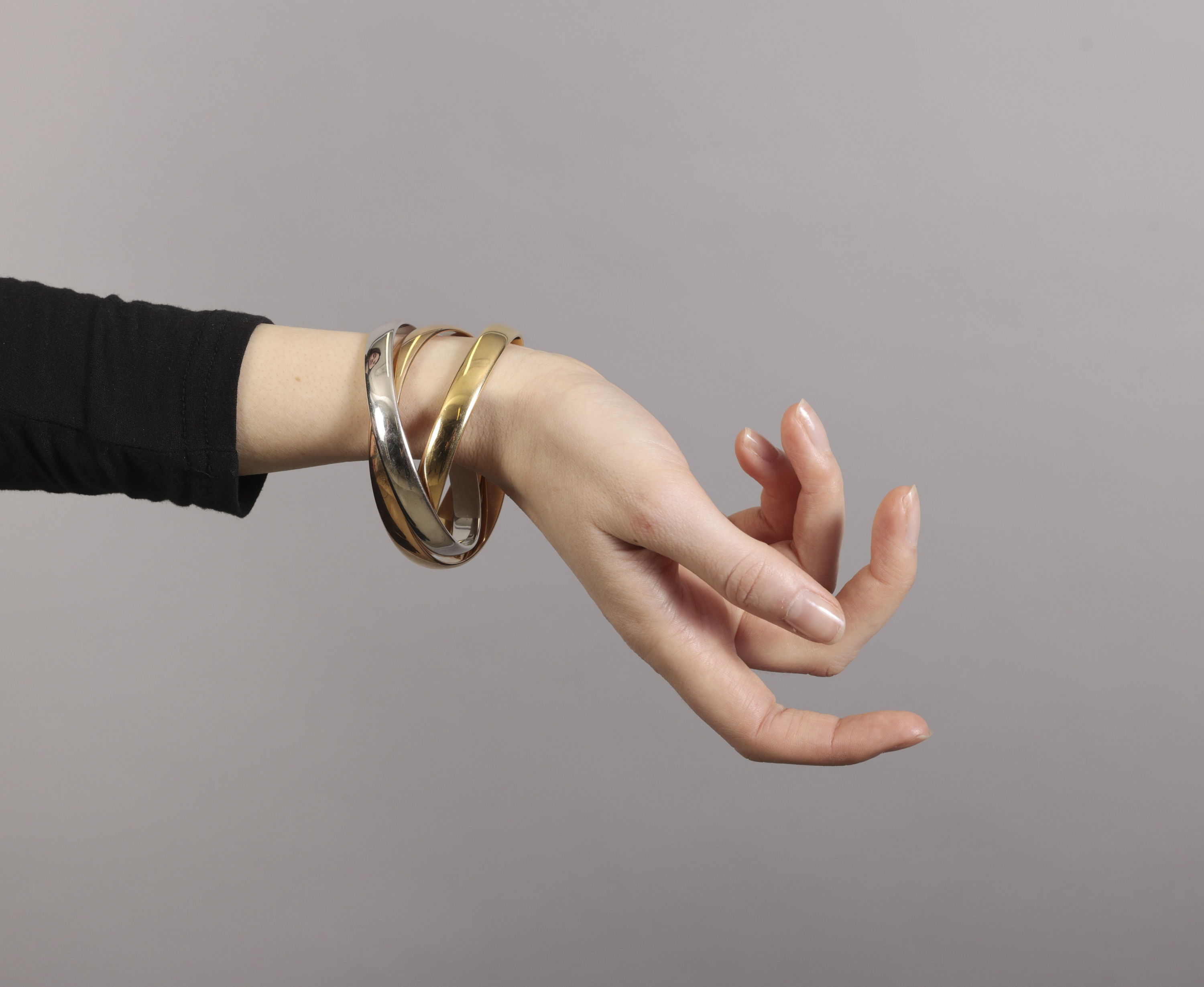 A GOLD 'TRINITY' BANGLE, BY CARTIER Composed of three interlocking polished 18K tri-coloured gold - Image 5 of 6