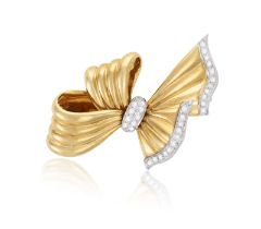 A DIAMOND BOW BROOCH Designed as a stylised polished gold bow with fluted detailing, highlighted