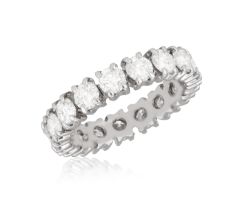 A DIAMOND ETERNITY RING Composed of a continuous row of brilliant-cut diamonds within four-claw