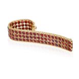 A GARNET AND GOLD BRACELET, CIRCA 1950 The wide band collet-set with circular-cut garnets, to fine-