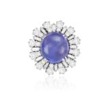 A SAPPHIRE AND DIAMOND CLUSTER RING, CIRCA 1960 The oval-shaped sapphire cabochon weighing