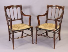 A pair of 19th century beech spindle-back carver chairs each with a woven-rush seat, & on ring-