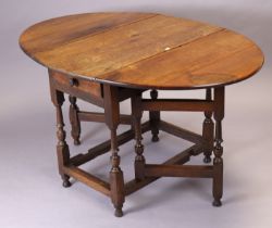 An early 20th century oak oval gate-leg dining table fitted with an end drawer, & on baluster-turned