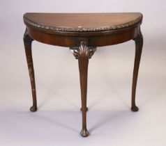 A mahogany card table with a demi-lune fold-over top, & on three slender carved cabriole legs & claw