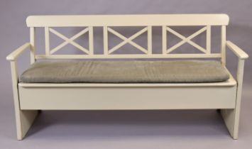 An off-white painted wooden bench with a trellis-type open back, loose cushion to the hinged box