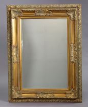 A large gilt frame rectangular wall mirror with a raised foliate border, & inset with a bevelled