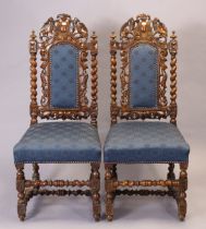 A pair of Carolean-style carved oak side chairs each with a padded seat & back, & on turned legs