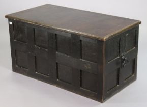 A vintage ebonised stained oak travelling trunk with a hinged lift-lid, panelled front & sides, &