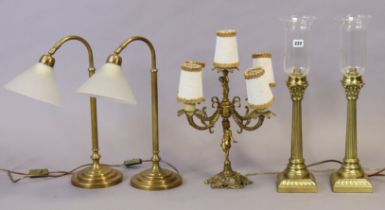 A pair of brass Corinthian-style table lamp bases each with a glass shade; another pair of brass