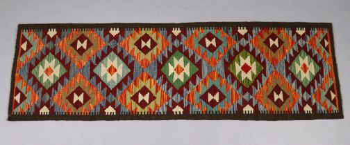 A Maimana Kilim runner of ochre ground with repeating multicoloured geometric design within a single