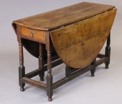 An 18th century oak gate-leg dining table with oval top, fitted end drawer, on turned supports