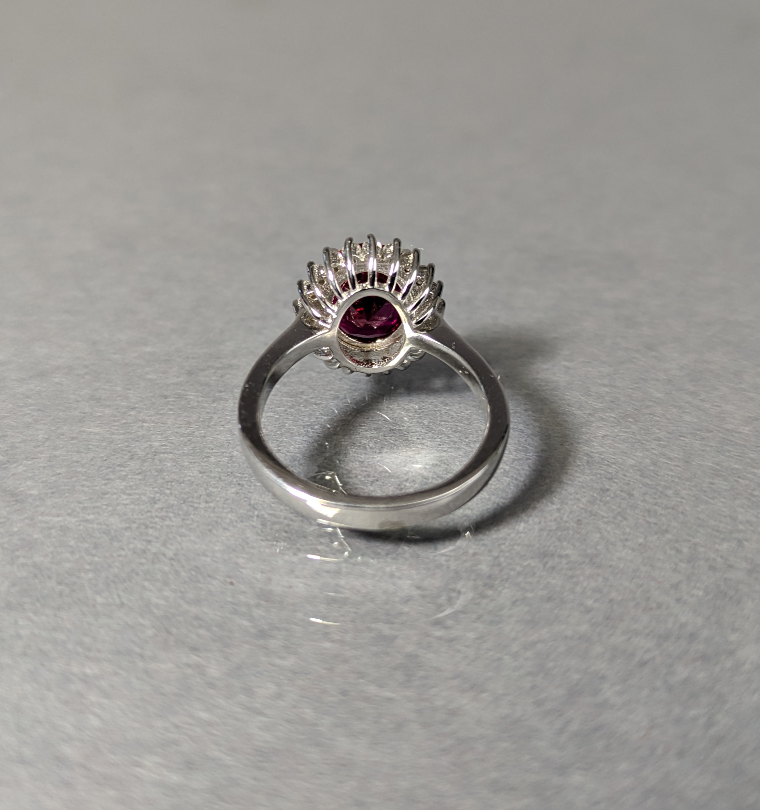 A dress ring set oval-cut cubic zirconium of deep red colour, within a border of small white stones, - Image 3 of 3
