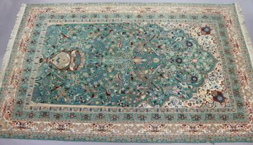 A Persian carpet of pale green and ivory ground, the central field with birds amongst flowers, in