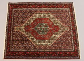 A northwest Persian Senneh rug of madder ground with repeating lozenge designs in multiple narrow