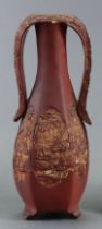 A 20th century Chinese yixing two-handled hexagonal baluster vase of red ground with carved relief