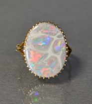 An opal ring, the oval-cut stone approx. 18mm X 14mm, claw-set to a yellow metal shank marked "18ct